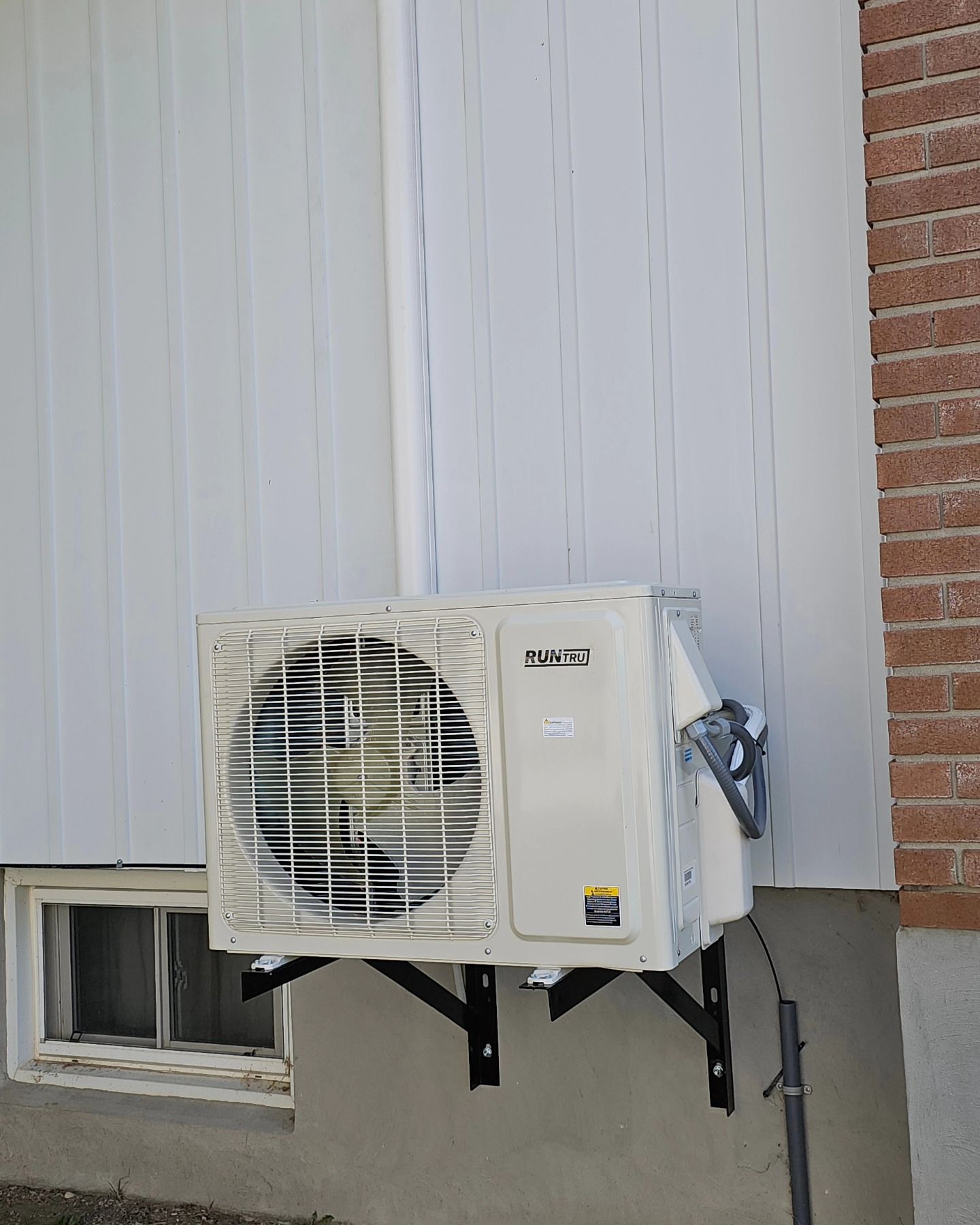 Air conditioning unit mounted on a building's exterior, next to a window.