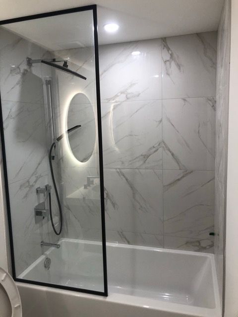 Une salle de bain avec baignoire, douche, miroir et WC.