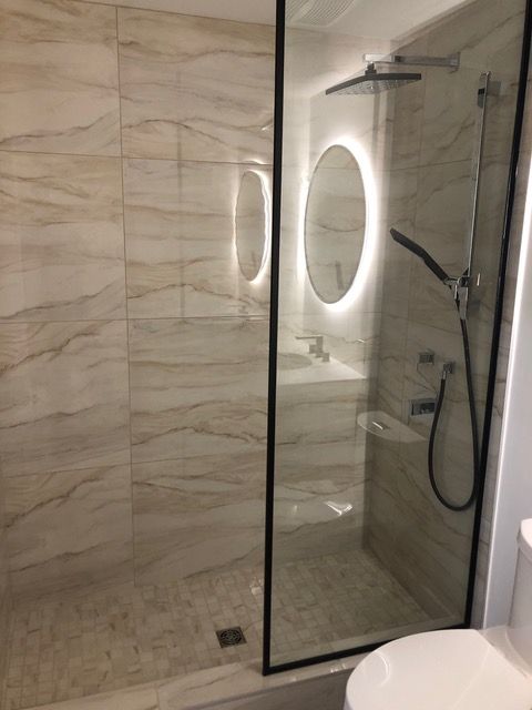 Une salle de bain avec douche à l'italienne, WC, lavabo et miroir.