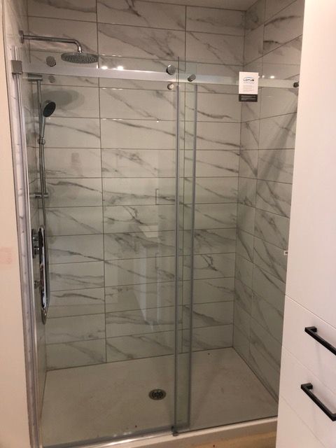 Une cabine de douche avec une porte coulissante en verre dans une salle de bain.
