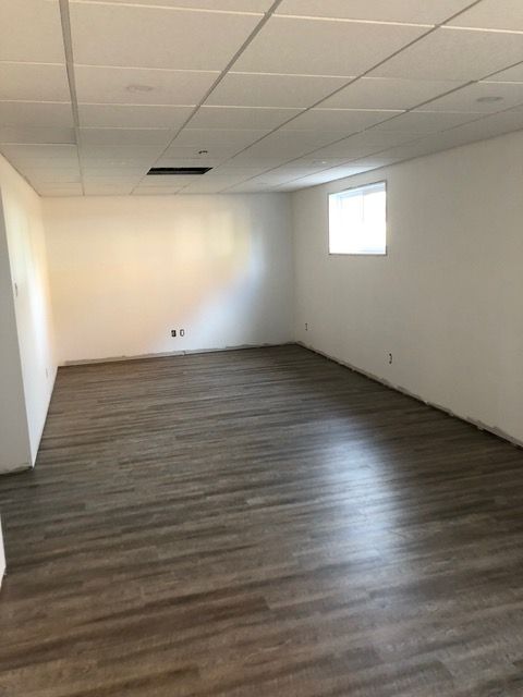 Une pièce vide avec du parquet et des murs blancs.