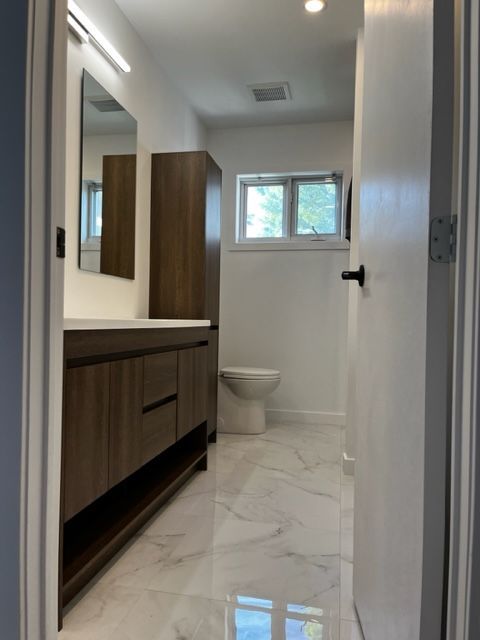 Une salle de bain avec des toilettes, un lavabo et un miroir