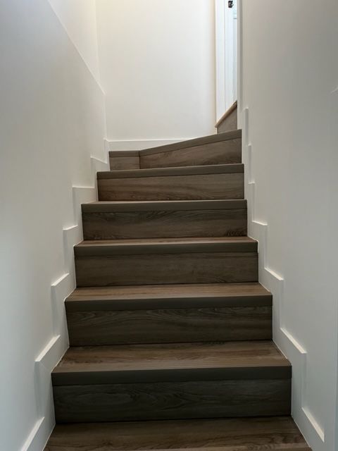 Un ensemble d'escaliers en bois menant à un mur blanc.