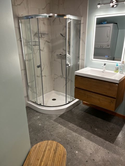 Une salle de bain avec douche, lavabo et miroir.