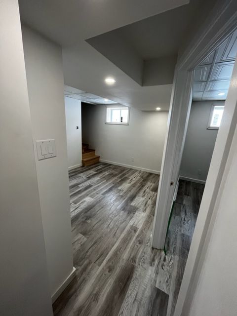 Un couloir dans un sous-sol avec planchers de bois franc et une fenêtre.