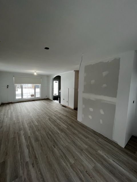 Un salon vide avec un plancher en bois et des murs blancs.