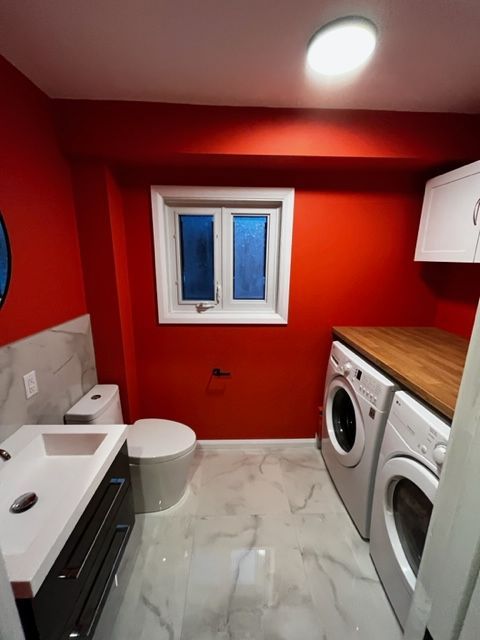 Une salle de bain avec des murs rouges et une laveuse et une sécheuse