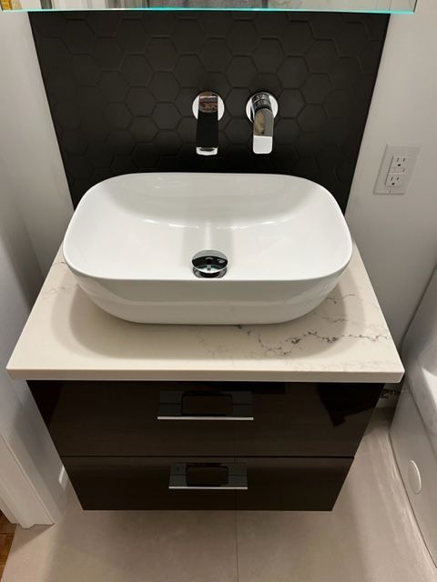 Un lavabo de salle de bain est posé sur un meuble noir.