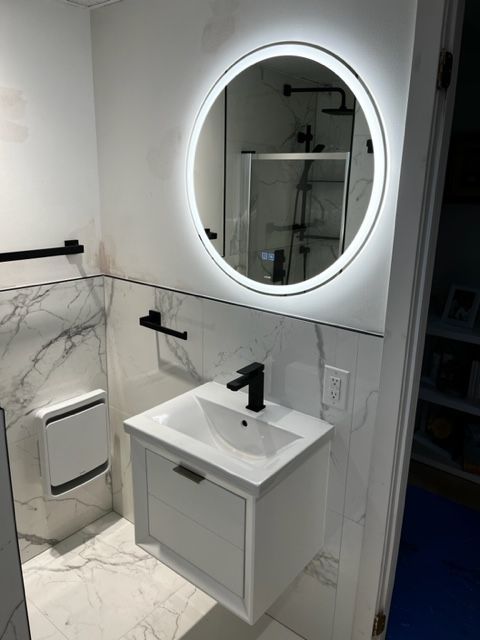 Une salle de bain avec un lavabo et un miroir rond.