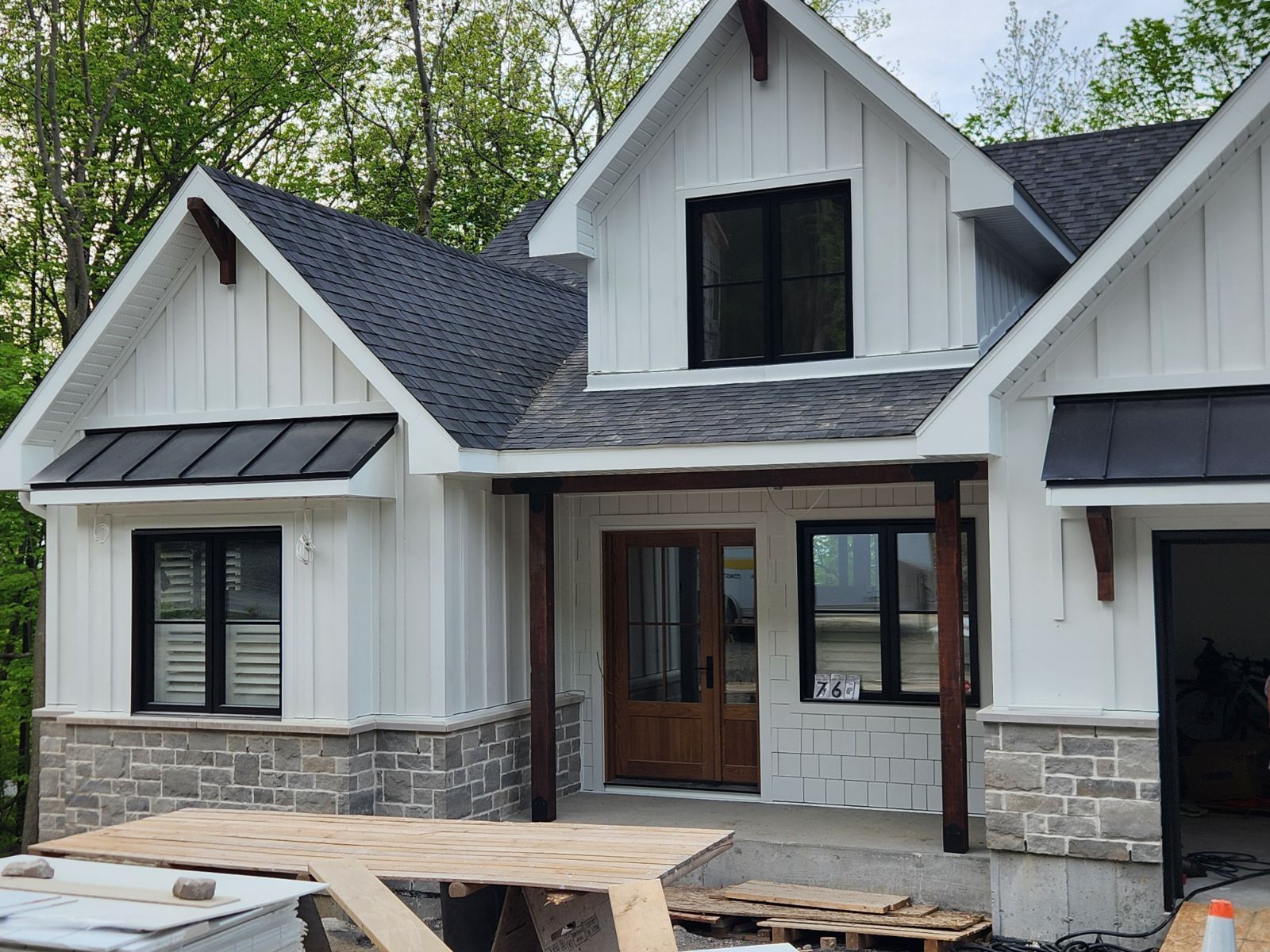 Ferme blanche avec garniture noire, base en pierre et porte d'entrée en bois.