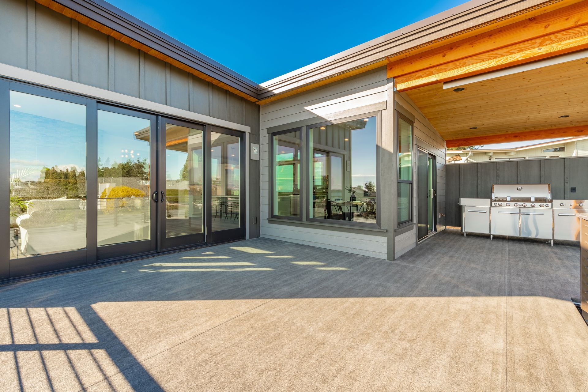 Une grande maison avec beaucoup de fenêtres et de portes coulissantes en verre.