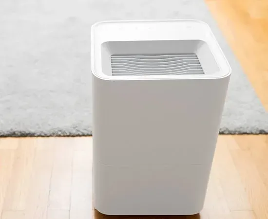 A white trash can is sitting on a wooden floor next to a rug.