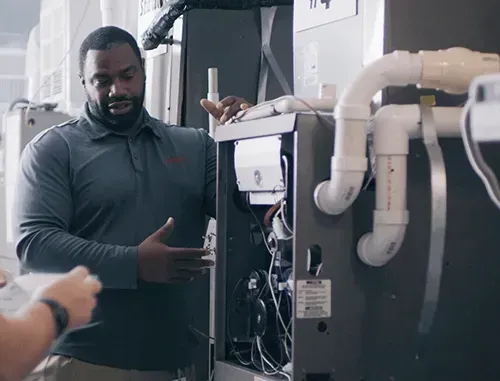 A man is standing next to a furnace and talking to another man.
