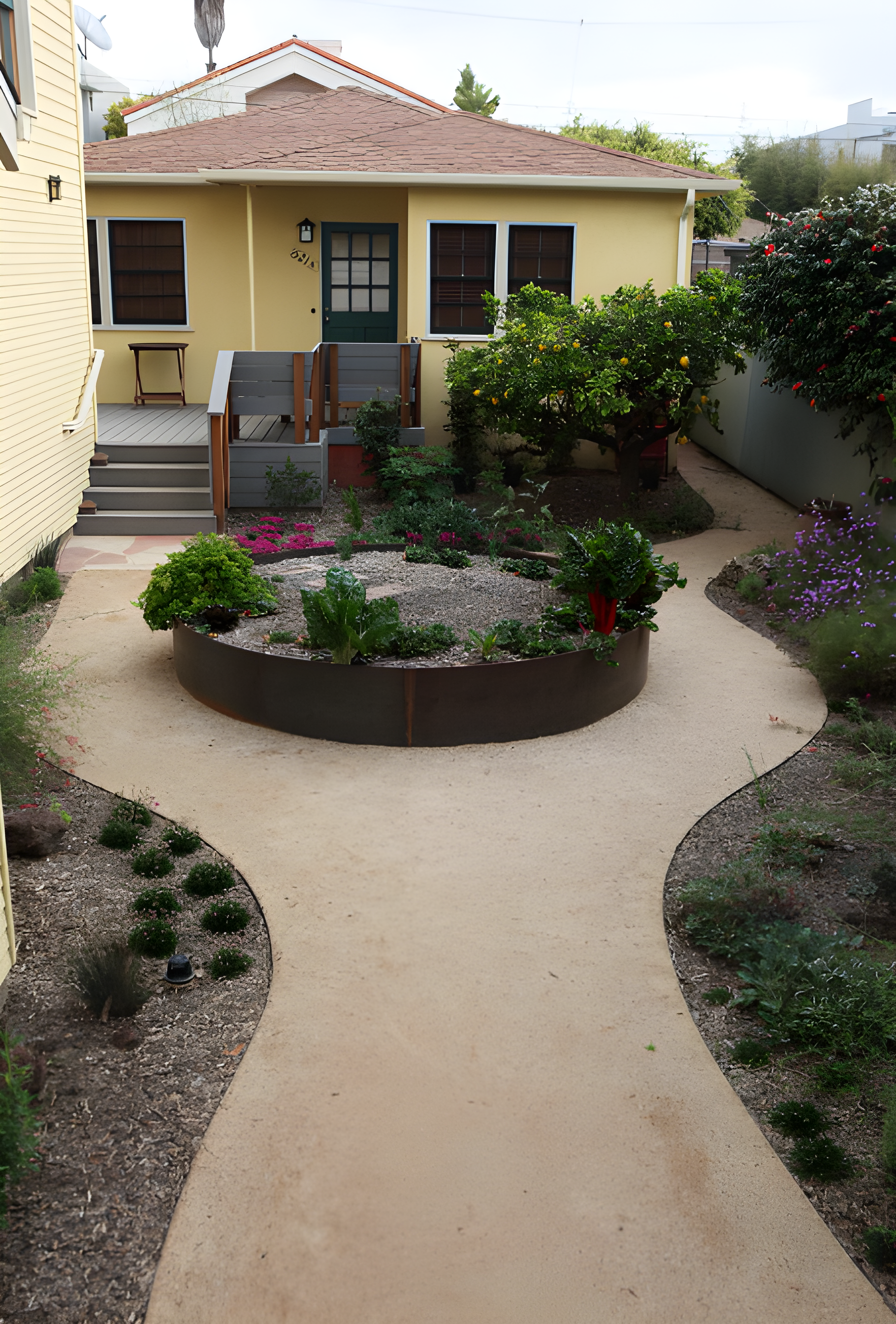 Casa amarilla con jardín circular y caminos de arena.