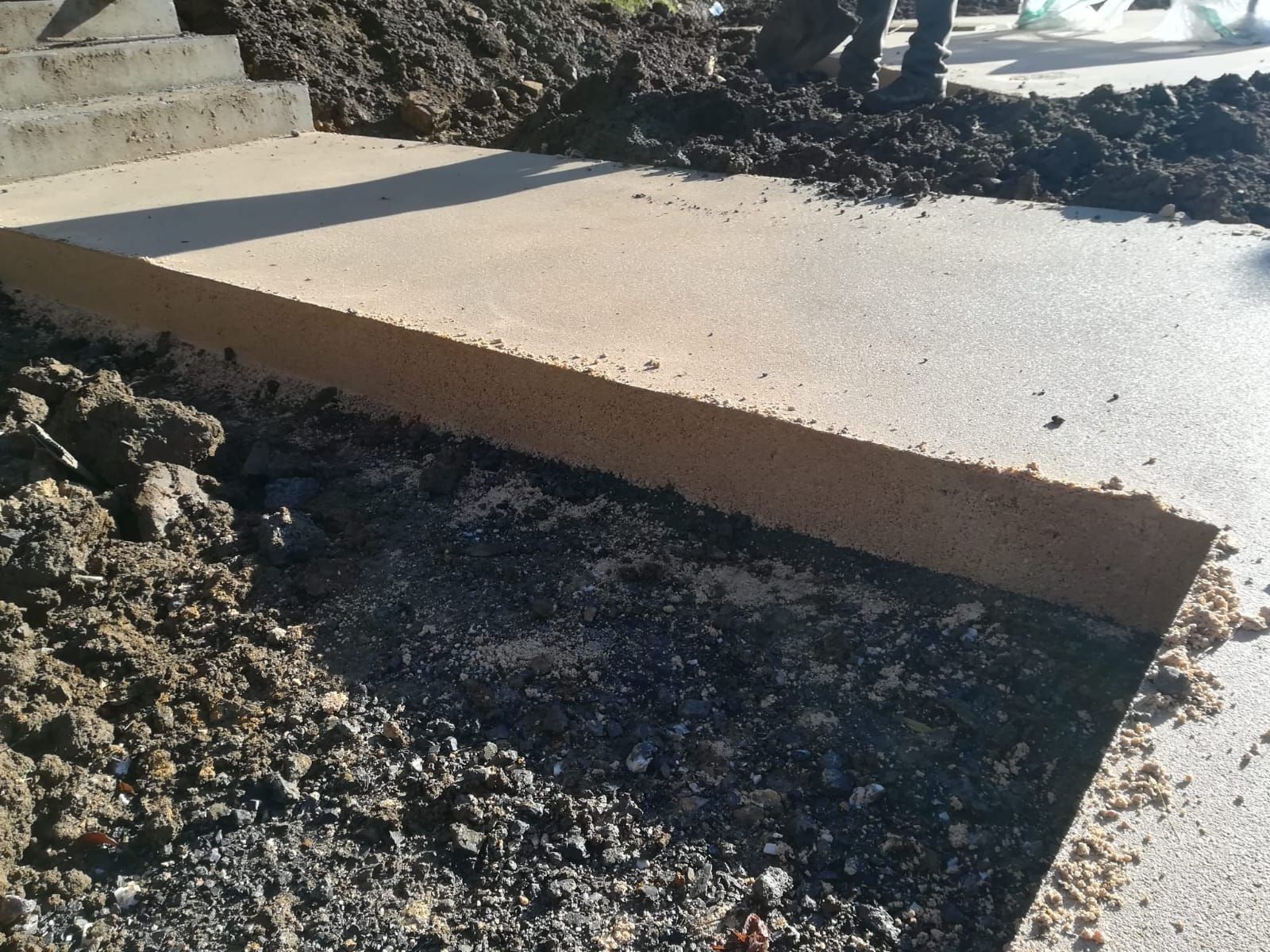 Sendero de tierra compactada  que atraviesa una zona boscosa, de color marrón con un borde de grava.