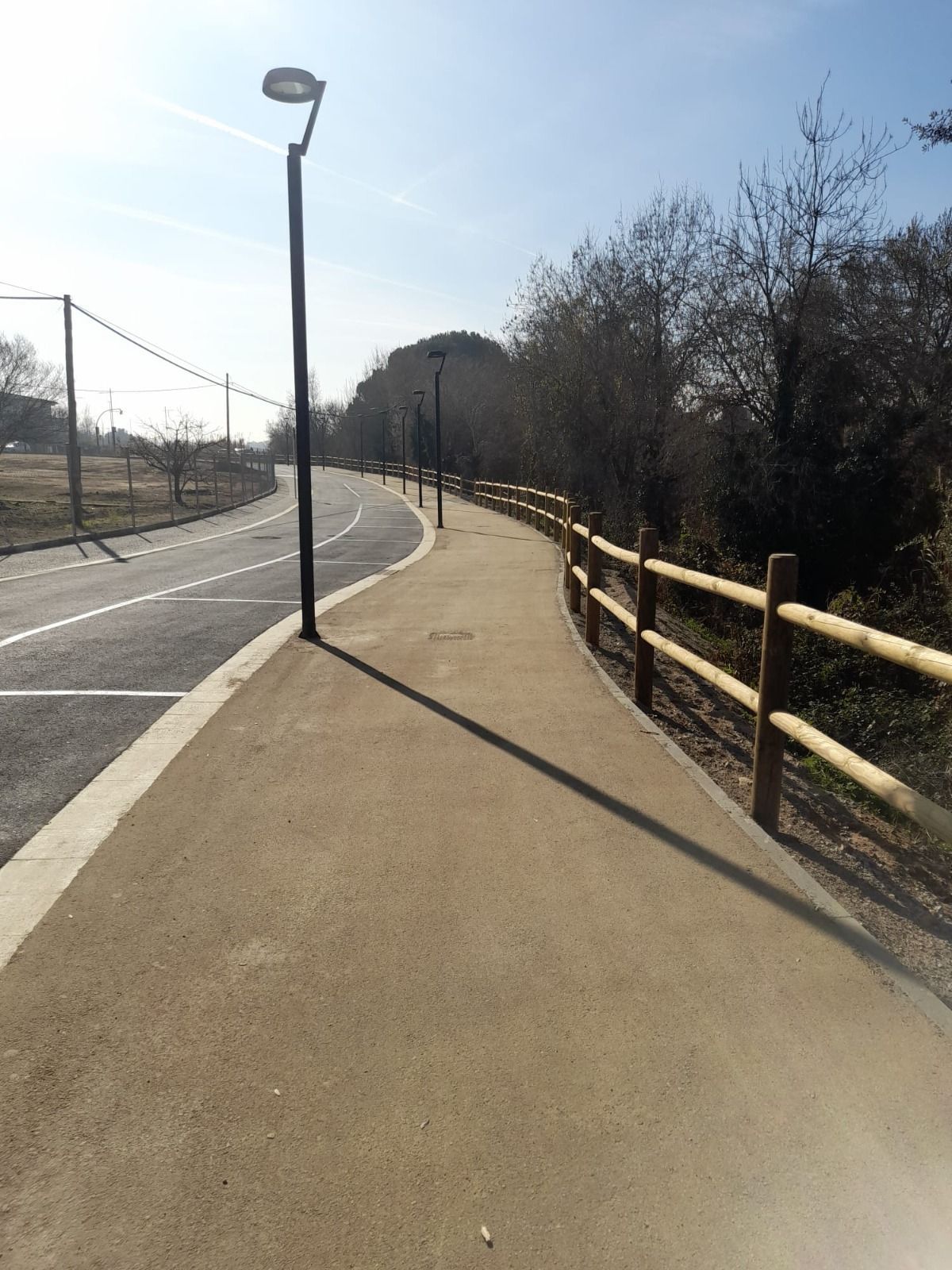 Un sendero sinuoso que atraviesa un jardín con una valla de madera y diversas plantas.