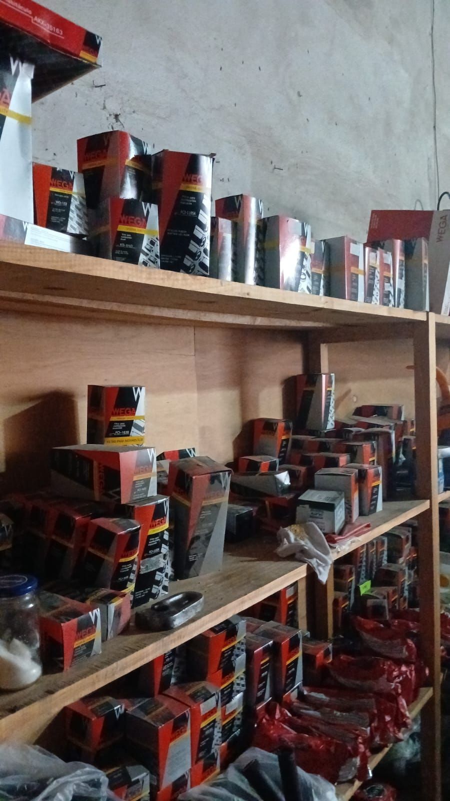 Estanterías repletas de piezas de automóviles en cajas y latas, en su mayoría de color rojo y negro.
