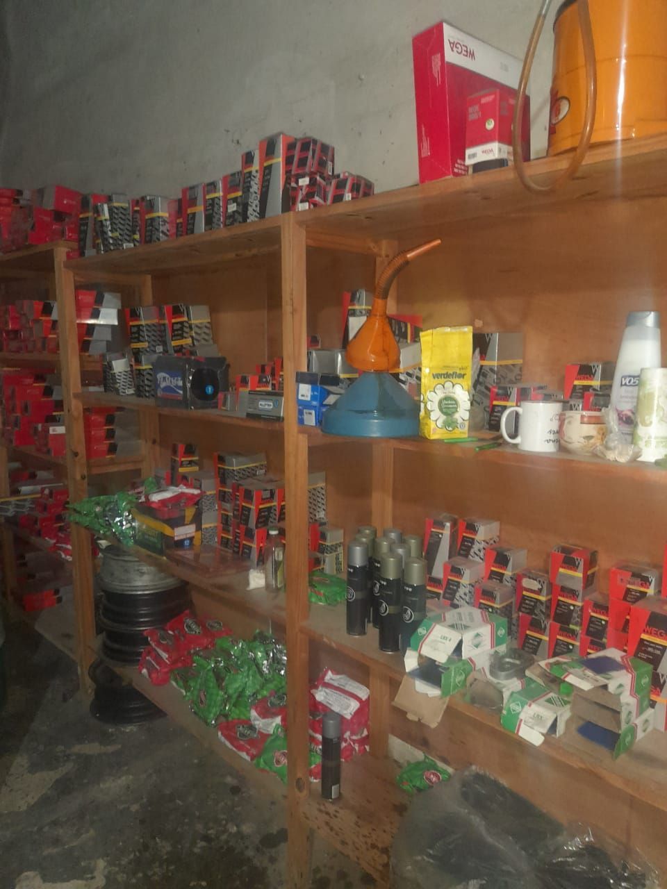 Estantes llenos de diversas piezas de automóviles, herramientas y suministros dentro de un área de almacenamiento.