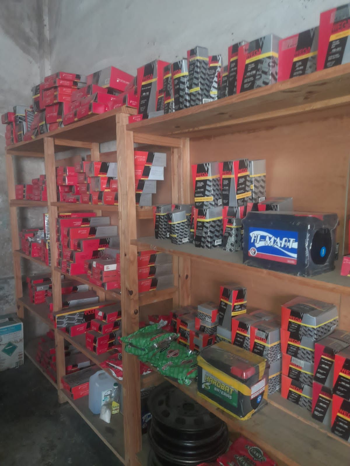 Estantes repletos de piezas de automóviles y baterías de automóviles en cajas rojas y negras en un almacén.