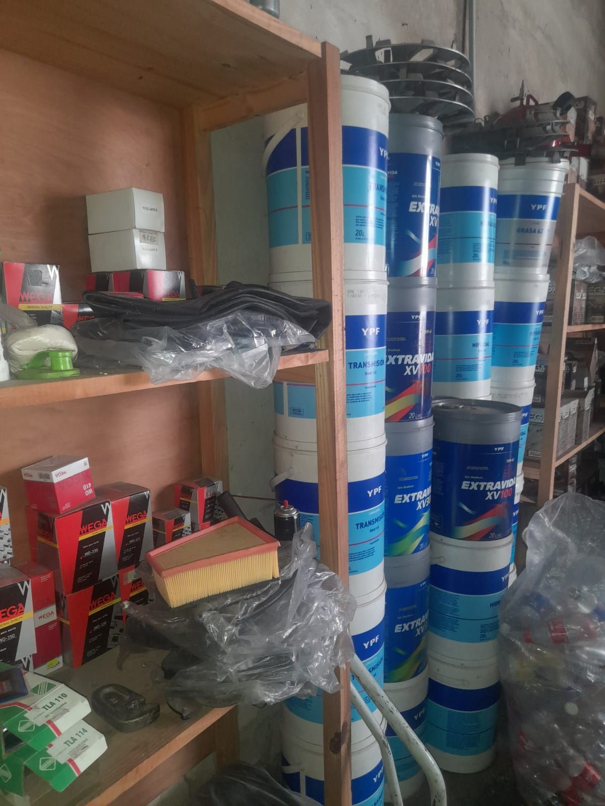 Estanterías repletas de autopartes y contenedores cilíndricos apilados, en una tienda.
