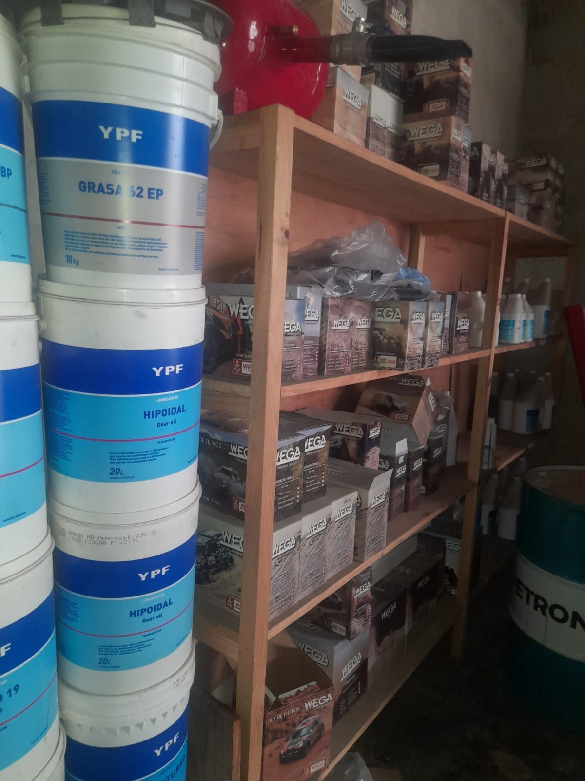 Estantes repletos de productos automotrices, incluyendo cubos y cajas de grasa. Artículos azules y blancos de la marca YPF.