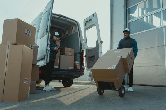 Two delivery men are loading boxes into a van.
