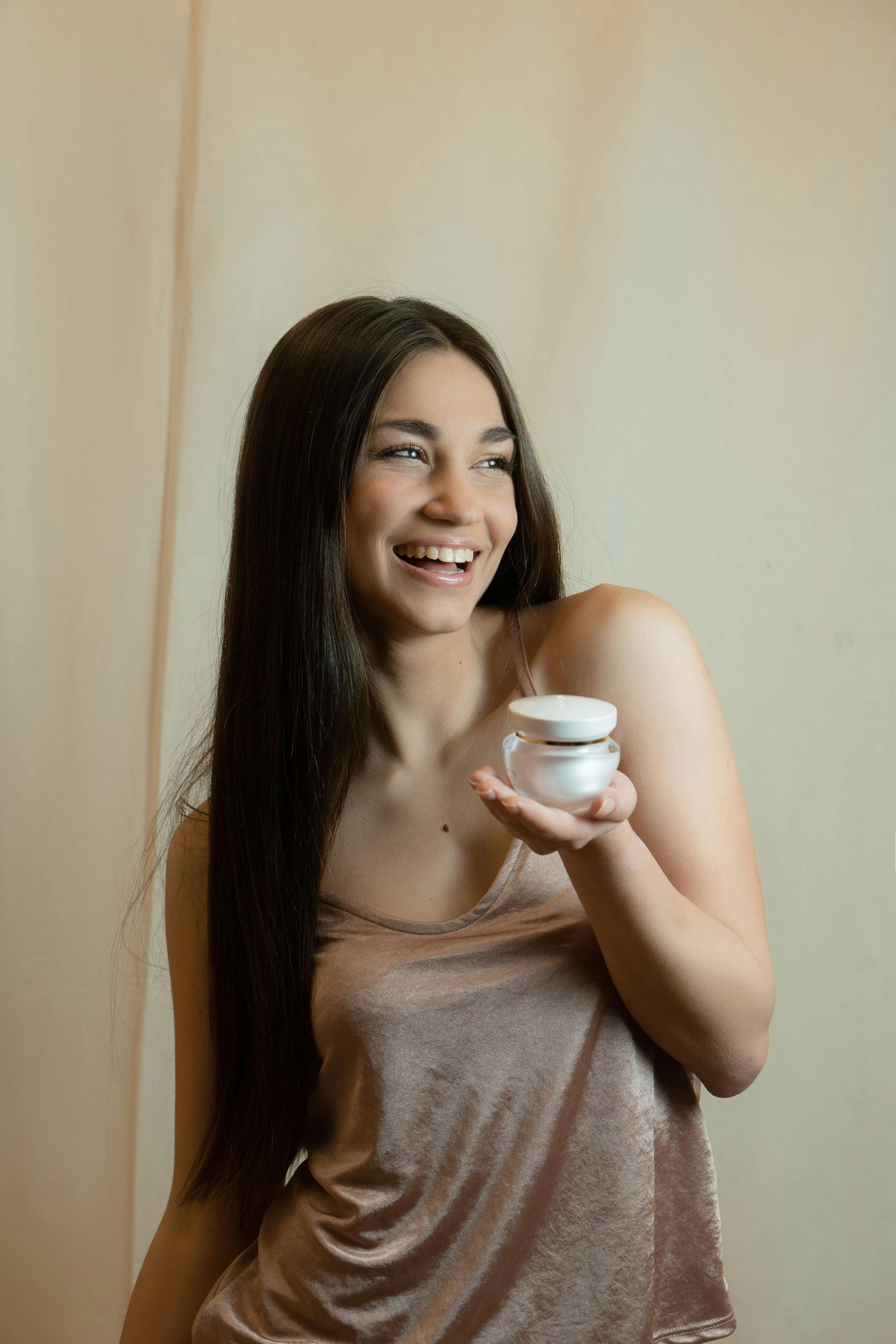 A woman is holding a jar of cream in her hand.