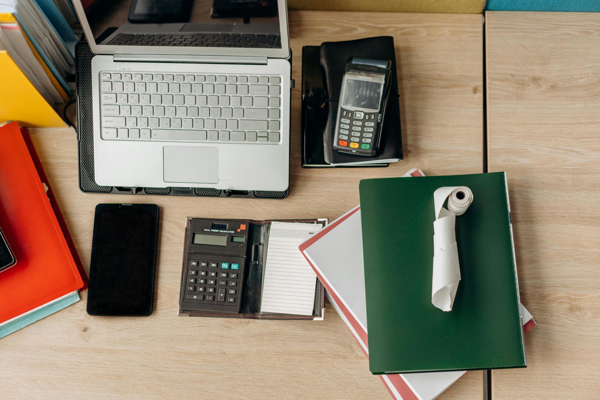 A desk with a laptop , calculator , cell phone , and papers.
