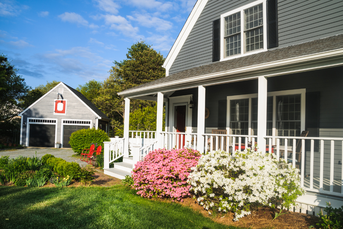 A large house with a large porch and flowers in front of it.