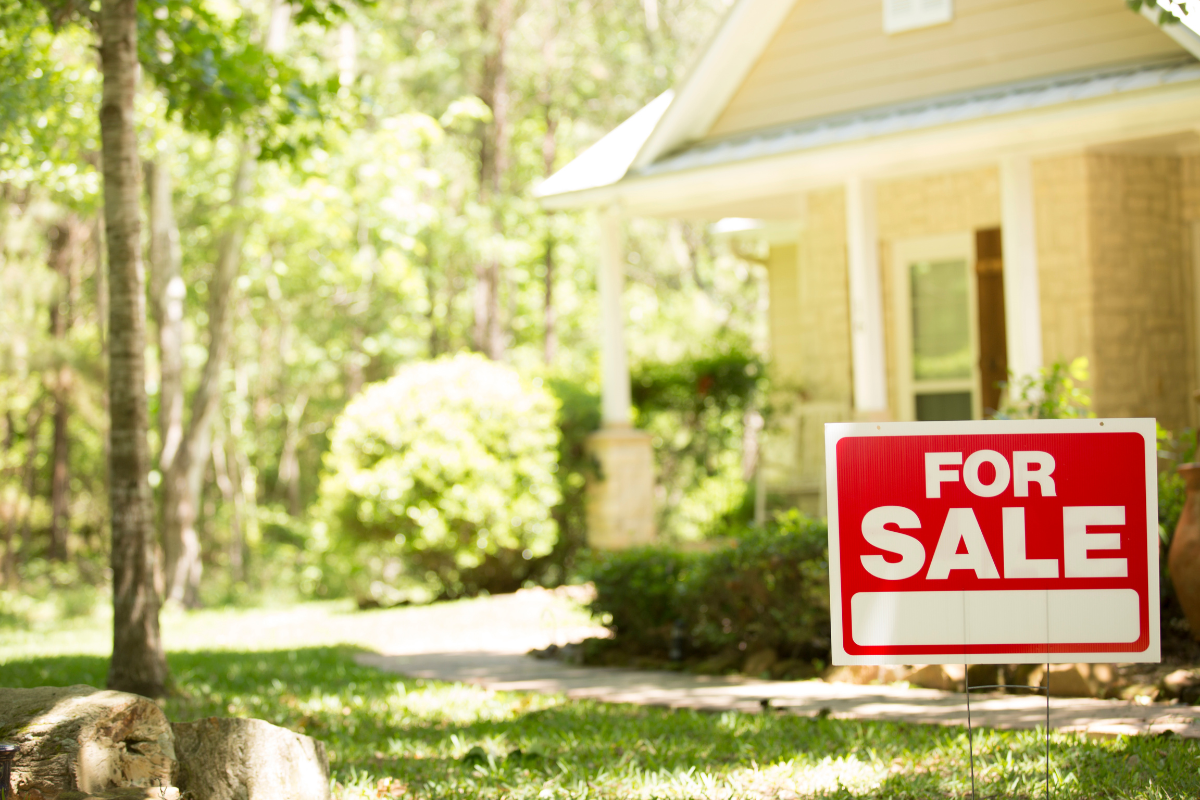 A for sale sign is in front of a house.