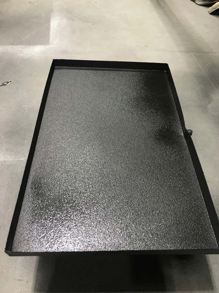 A black tray is sitting on a concrete floor.
