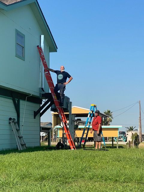 A man is standing on a ladder on the side of a house.