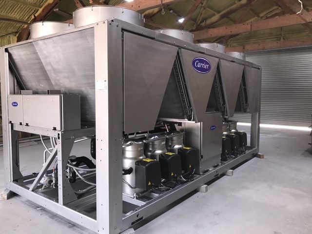 A large carrier air conditioner is sitting in a warehouse.