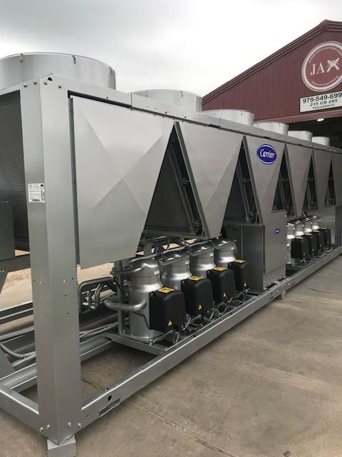 A large stainless steel machine is sitting in front of a red building.