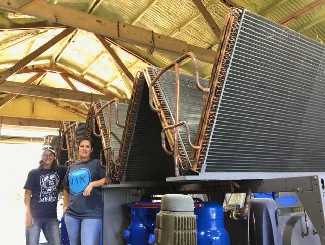A man and a woman are standing in front of a large metal structure.