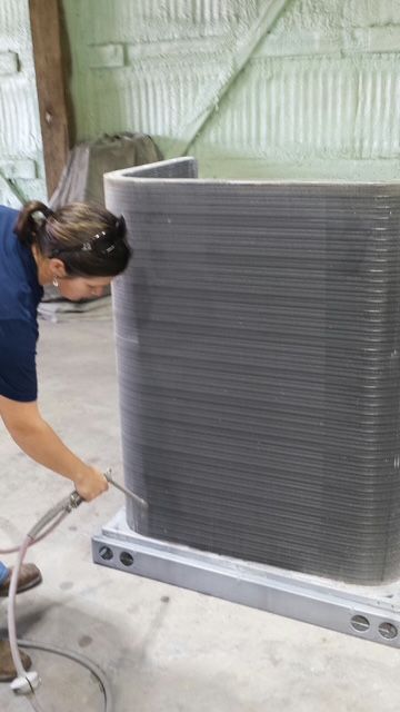 A woman is working on an air conditioner in a factory.