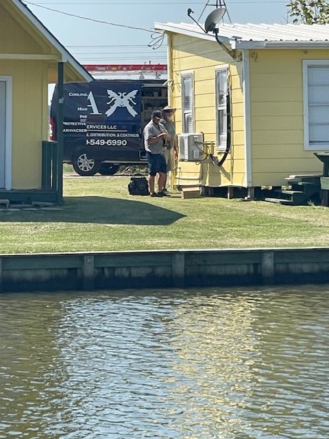 A man is standing in front of a house next to a body of water.