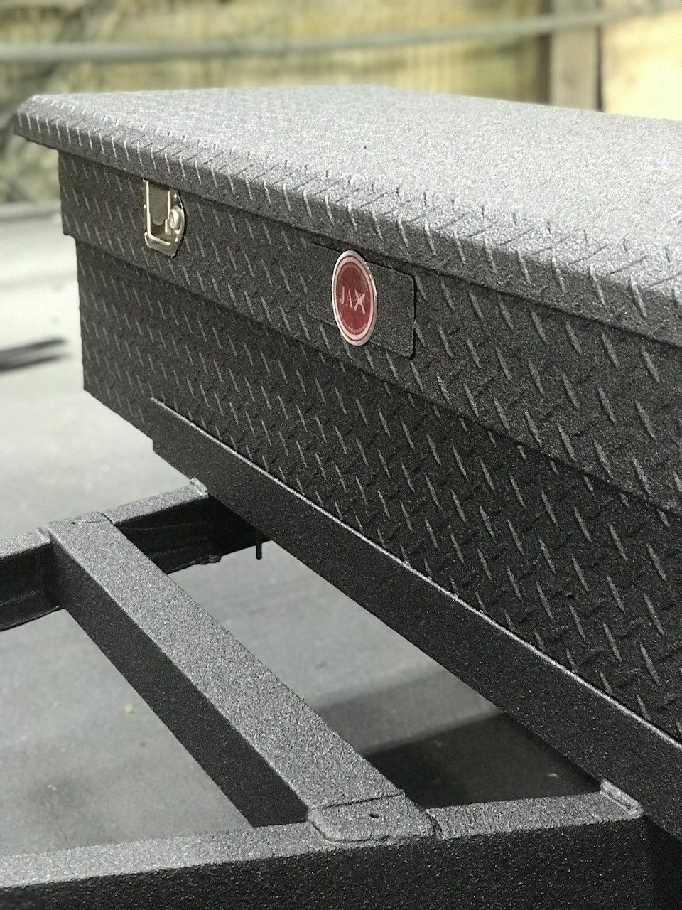 A metal toolbox is sitting on top of a trailer.