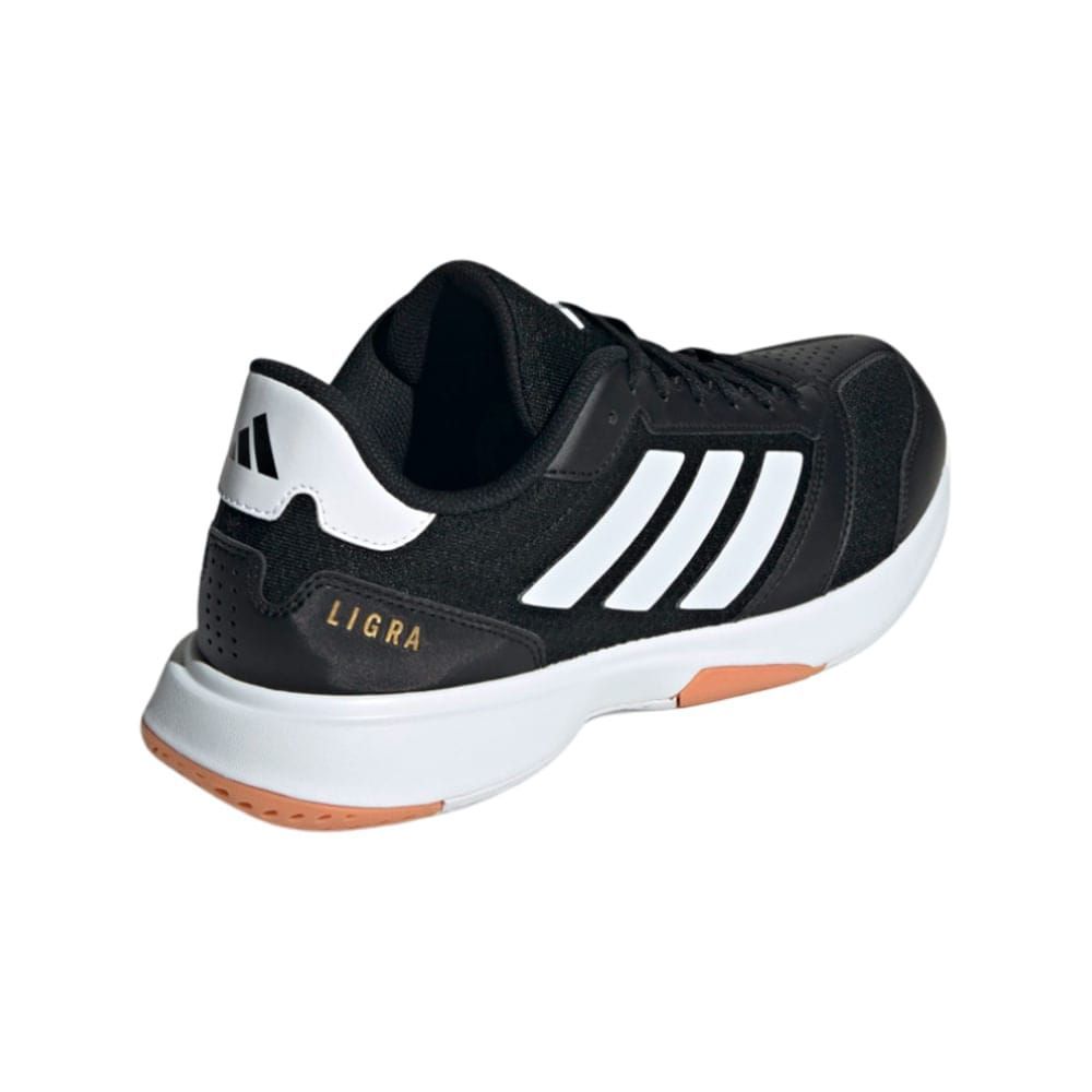 Zapatilla deportiva Adidas Ligra 7 en color blanco y negro con rayas blancas y suela marrón.