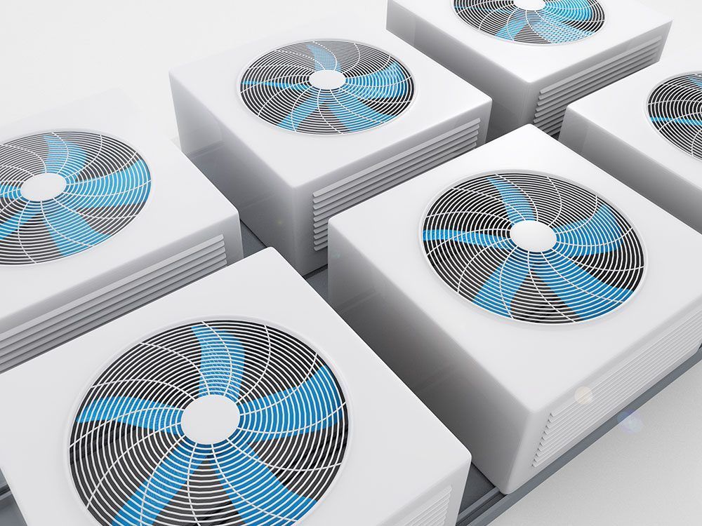 A high-angle view of multiple white outdoor HVAC condenser units with circular blue and black fan grilles.