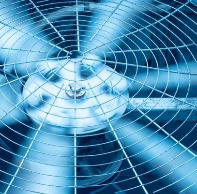 A close-up of a blue-toned industrial fan spinning behind a protective metal wire grid.