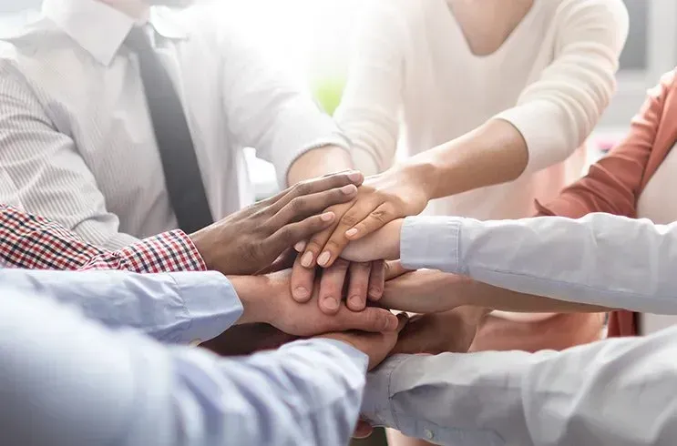 A group of people are putting their hands together in a huddle.