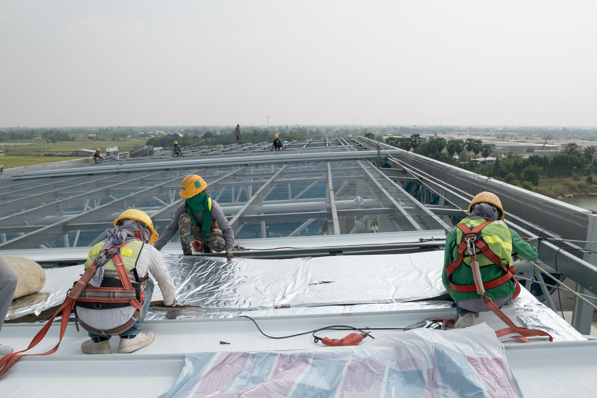 Construction workers installing roofing material on a metal structure