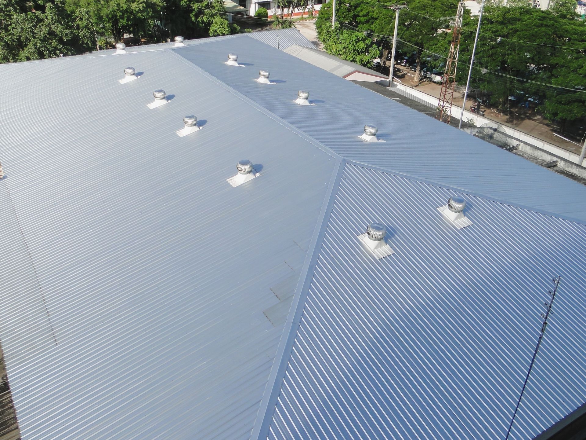 Silver corrugated metal roof with multiple ventilation fans