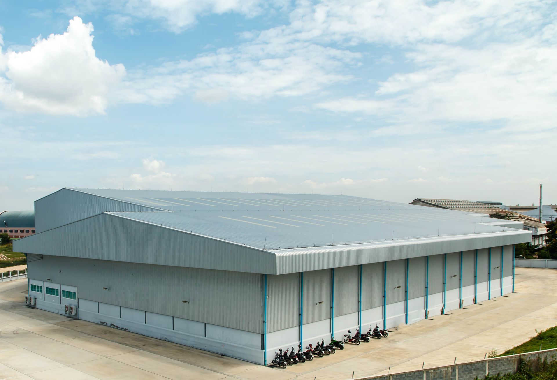 Large, gray industrial warehouse under a partly cloudy sky
