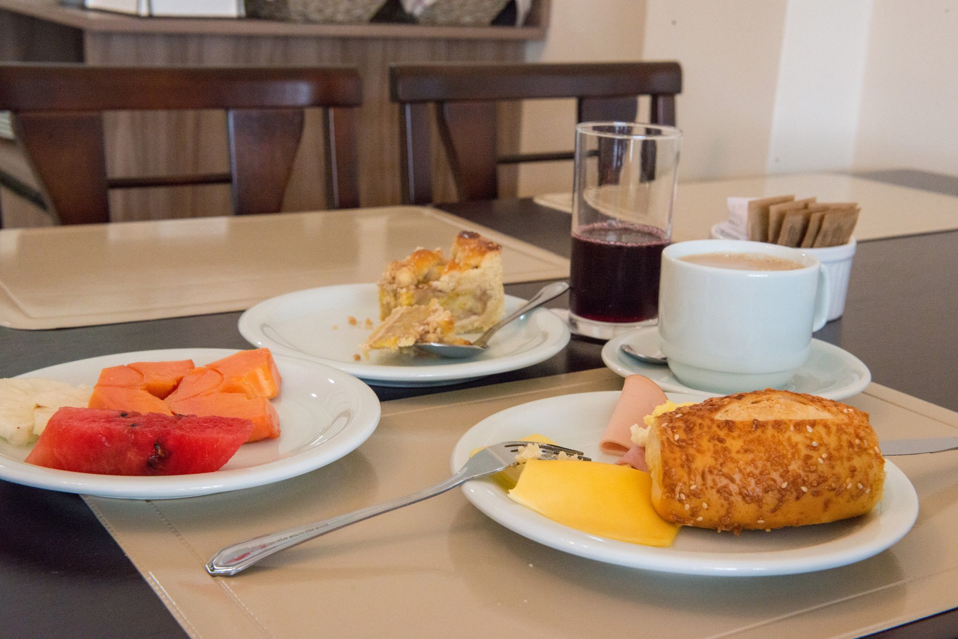 Mesa de café da manhã posta com frutas, doces, café e suco.