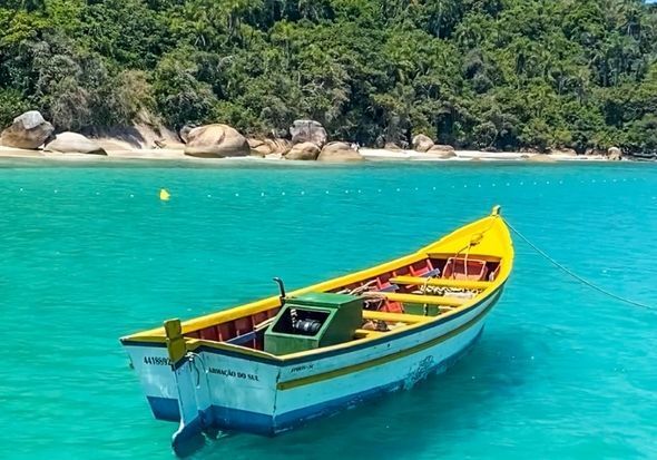 Um pequeno barco está flutuando na água perto de uma praia.