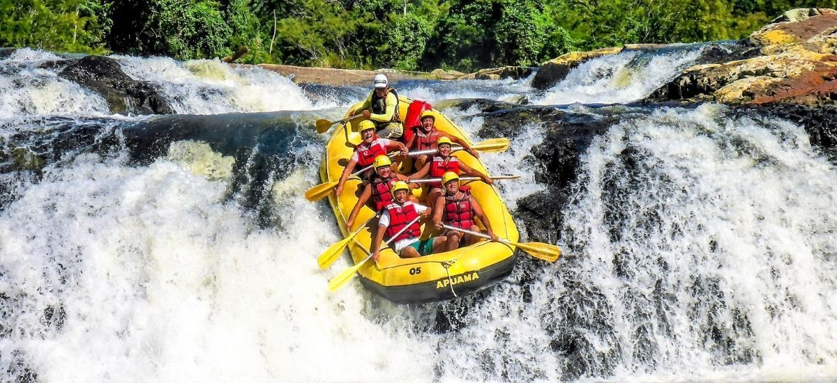 Um grupo de pessoas está descendo uma cachoeira em uma jangada amarela.