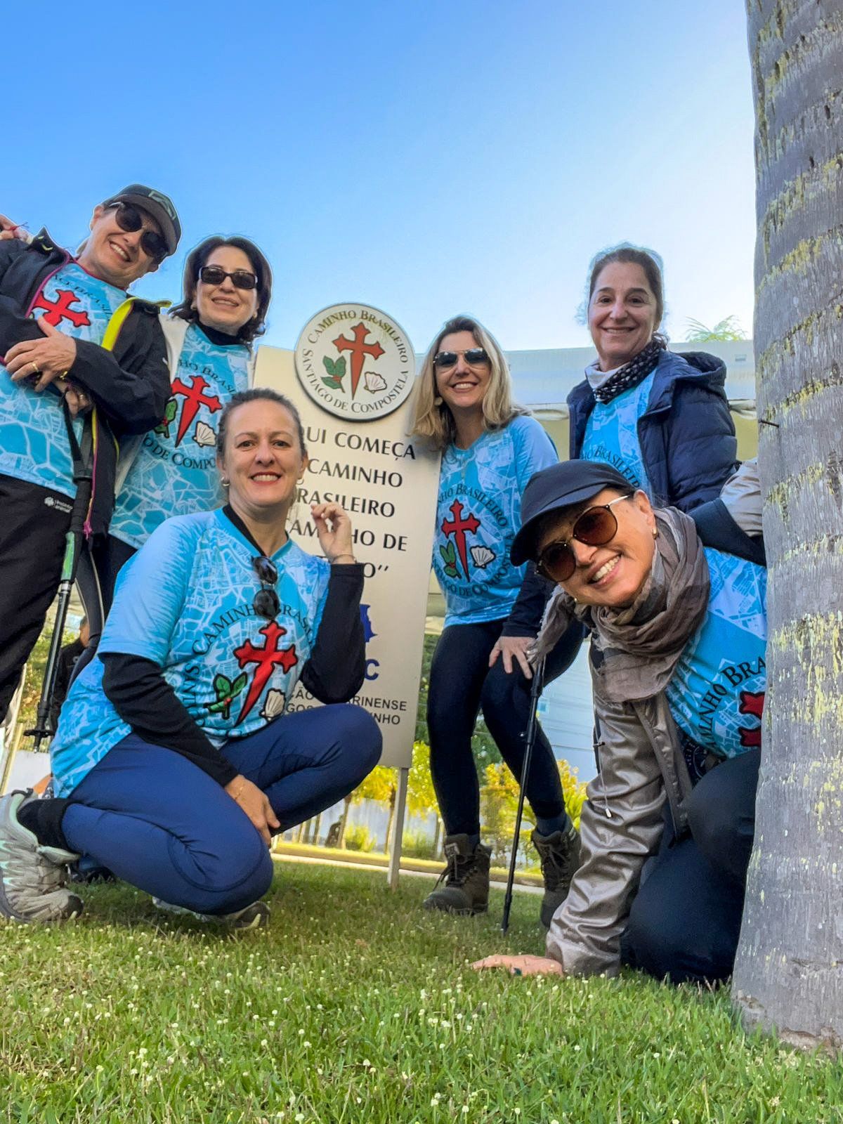 Um grupo de pessoas posa para uma foto em frente a uma placa.