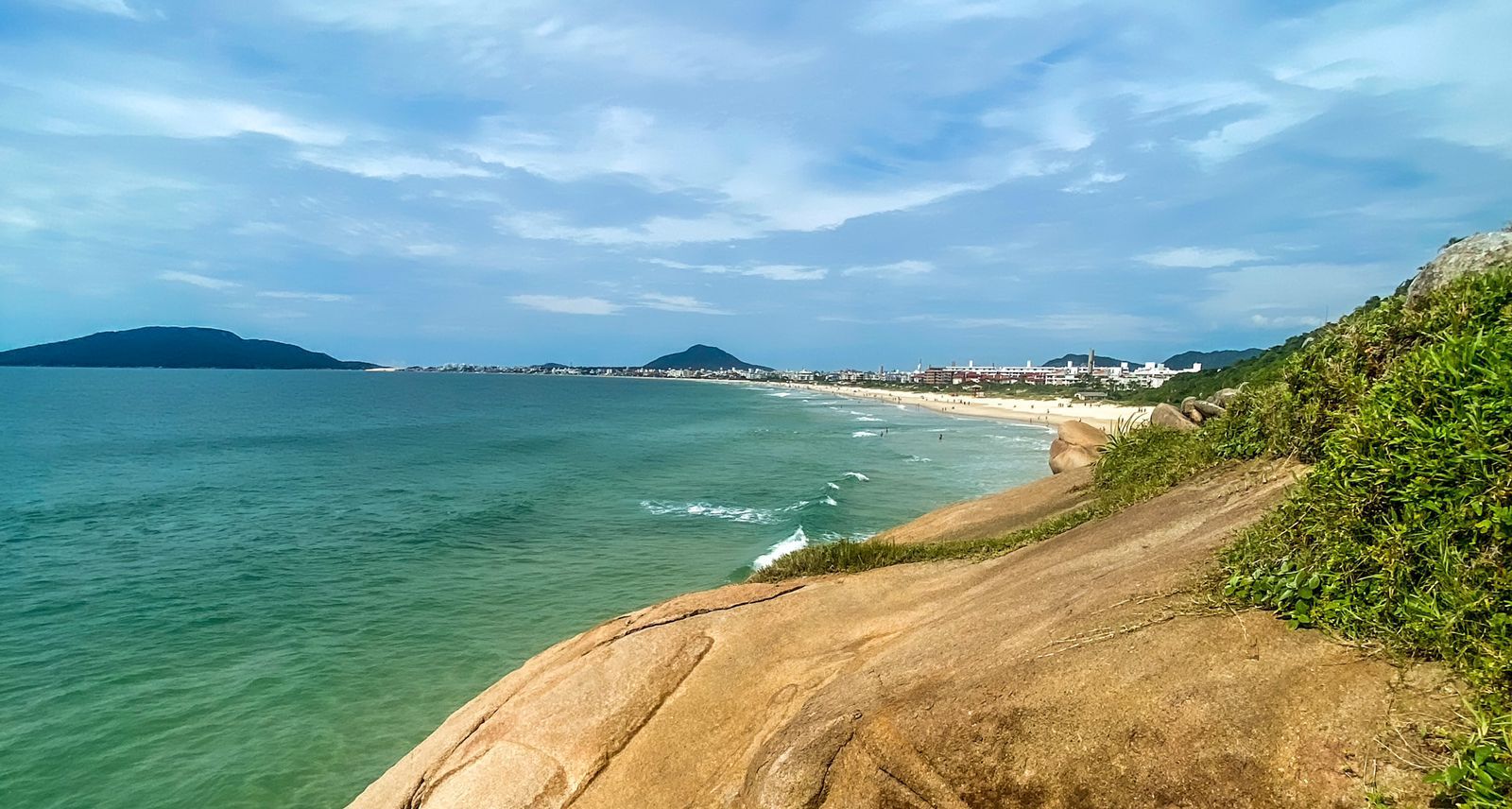 Uma vista de uma praia a partir de uma falésia com vista para o oceano.